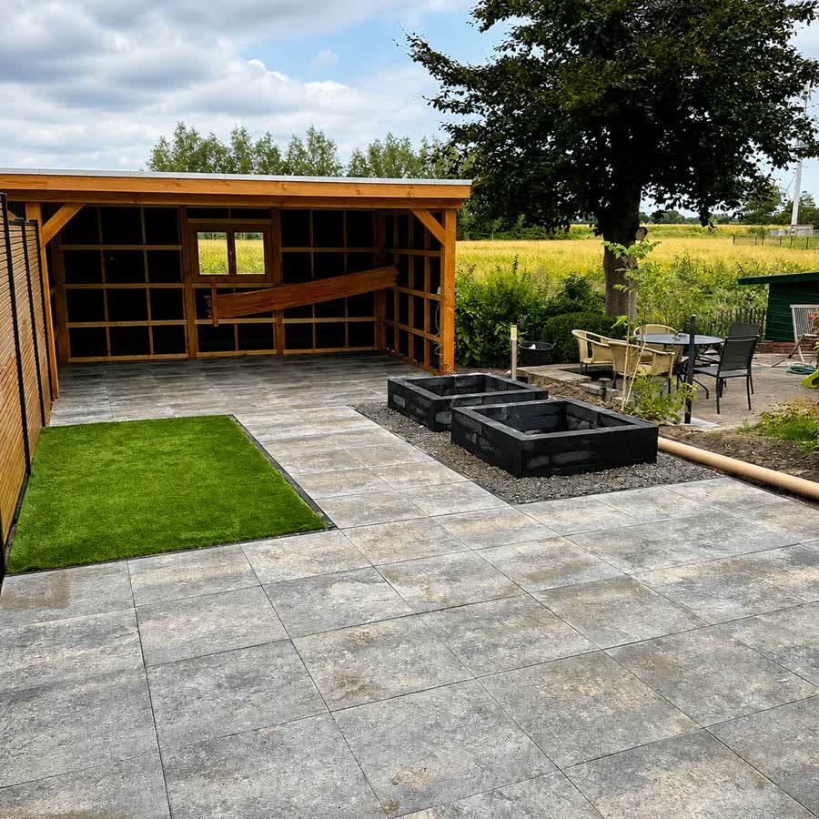 Ruim terras in grijze tegels met overkapping en kunstgras